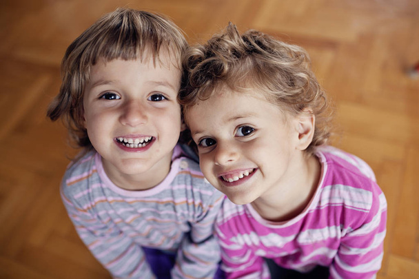 Δύο μικρά παιδιά κορίτσια σε ριγέ πουκάμισα στο σπίτι - Φωτογραφία, εικόνα