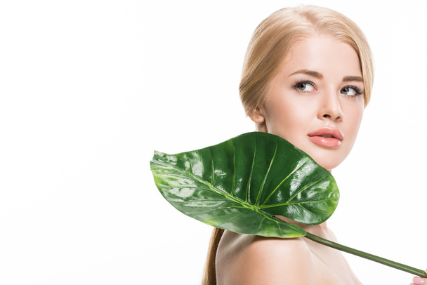 attractive naked girl holding fresh tropical leaf and looking away isolated on white - Фото, зображення