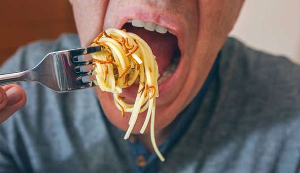 Man eating spaghetti with worms - Zdjęcie, obraz