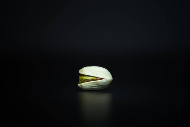 Single roasted crunchy pistachio on dark white background with space for your text - Foto, Imagen