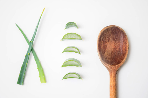 Aloe vera twigs and plant slices on white background with wooden spoon on the side - Fotoğraf, Görsel