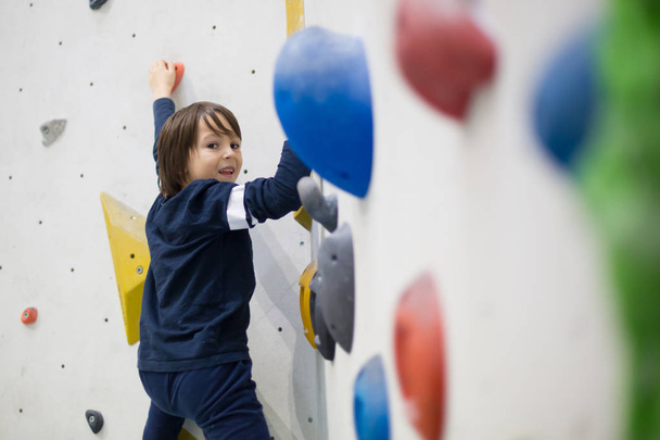 Sweet little preschool boy, climbing wall indoors, having fun, active children - Foto, afbeelding