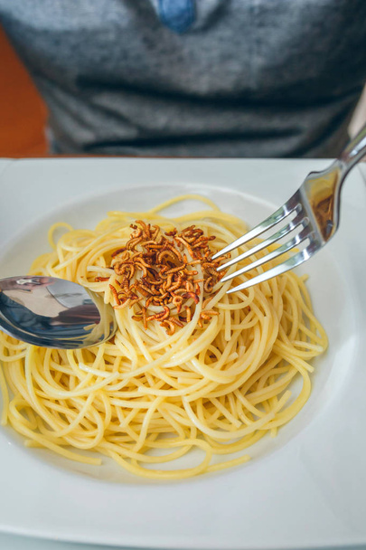 Mains d'homme mangeant des spaghettis aux vers
 - Photo, image