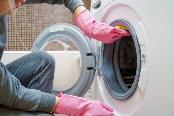 Photo of female hands in pink rubber glove washing washing machine - Zdjęcie, obraz