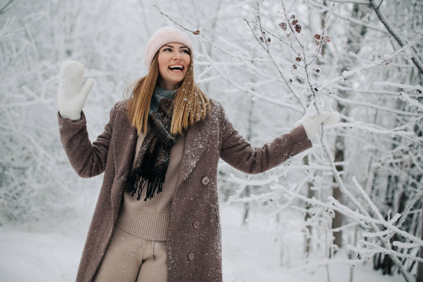 Portrait of smiling woman in hat on walk in winter forest - Фото, изображение