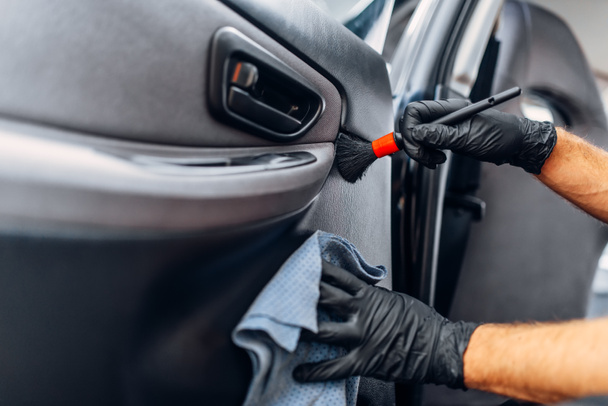 Araba iç carwash hizmetine otomatik detaylandırma. İşçi eldiven kapı fırça ile trim temizler - Fotoğraf, Görsel