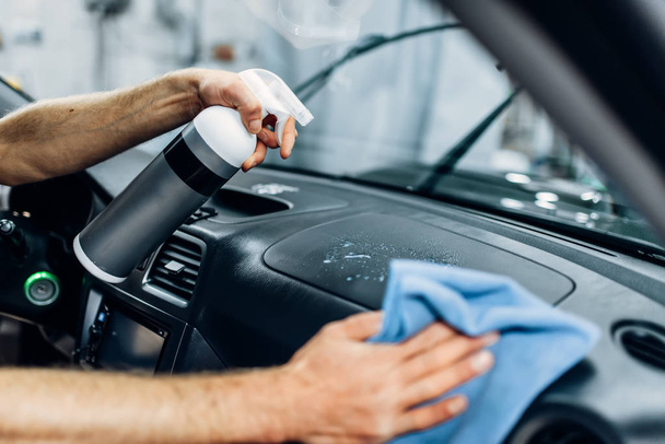 Auto detailing of car interior on carwash service. Worker in gloves cleaning salon with polishing spray - Fotoğraf, Görsel