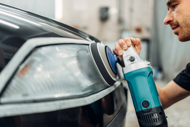 Détail automatique des phares de voiture sur le service de lavage de voiture. Travailleur nettoie le verre avec une machine à polir
 - Photo, image