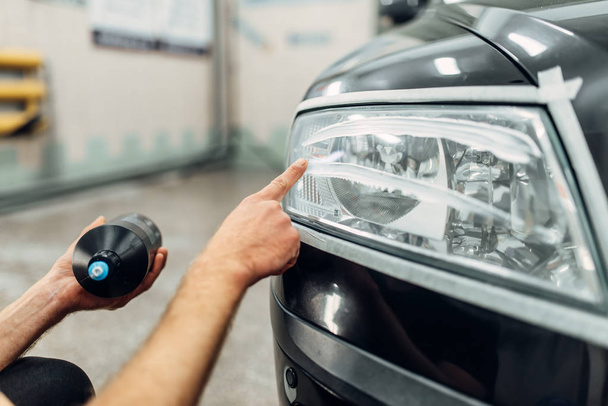 Auto detailing of car headlights on carwash service. Man smears polishing paste - Photo, image