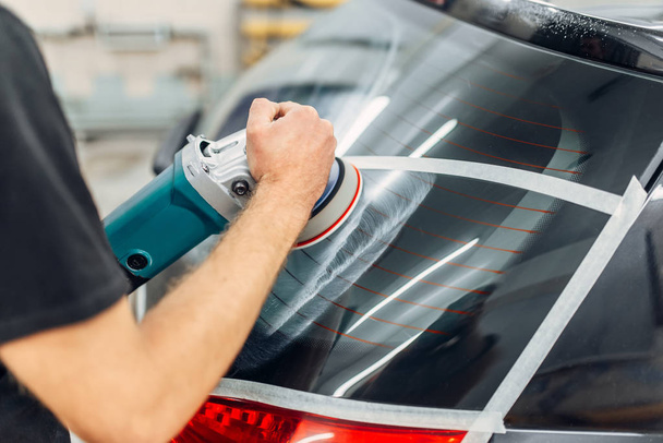 Worker with polishing machine removing the track from wiper blade on car window. Auto detailing on carwash service - Φωτογραφία, εικόνα