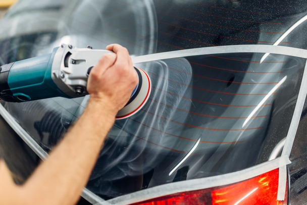 Εργαζόμενο με στίλβωση μηχανή αφαιρεί το κομμάτι από λεπίδα υαλοκαθαριστήρα στο παράθυρο του αυτοκινήτου. Auto λεπτομερώς υπηρεσία carwash - Φωτογραφία, εικόνα