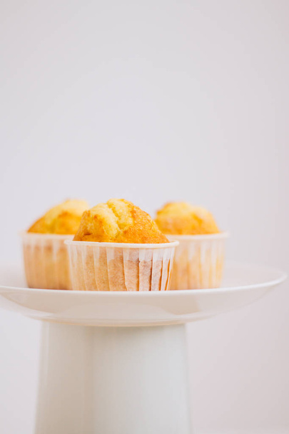 Muffins πορτοκαλιού σε μια τουρτιέρα, σε λευκό φόντο. Μινιμαλισμός - Φωτογραφία, εικόνα