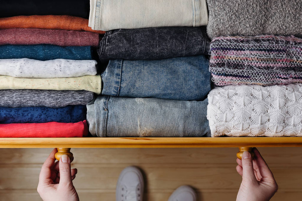 Vue aérienne de vêtements soigneusement commandés dans un tiroir en bois. Femme organisant des vêtements dans le tiroir
 - Photo, image
