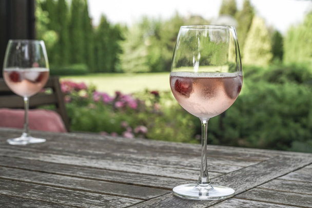 夏のガーデンで木製のテーブル ローズ ワイングラス - 写真・画像