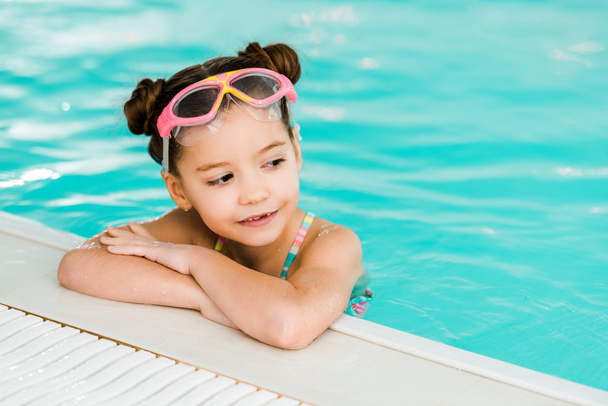 adorable child in googles swimming near poolside in swimming pool - Photo, Image