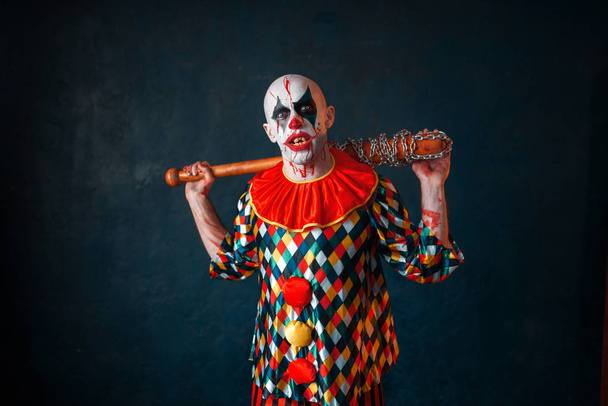 Szalony clown krwawe z kijem. Człowiek z makijażem w halloween kostium, maniak - Zdjęcie, obraz