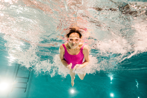 woman diving in googles underwater in swimming pool - Photo, Image