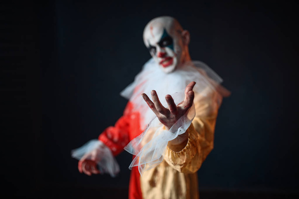 Szalony clown krwawe, osiągając przez ofiarę z jego rąk, widok z przodu. Człowiek z makijażem w karnawał kostium, szalony maniak - Zdjęcie, obraz