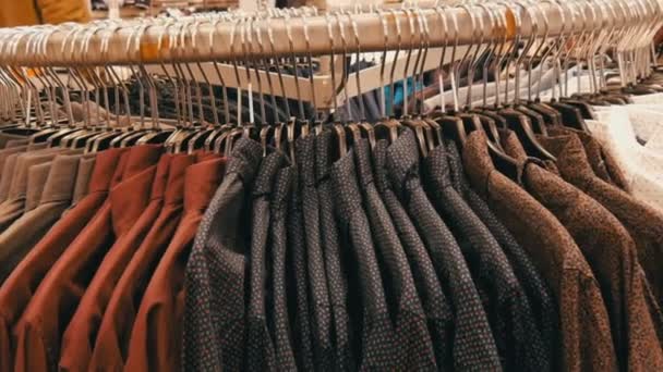Ряд различных модных мужских рубашек на огромной вешалке в мужском магазине одежды в торговом центре
. - Кадры, видео