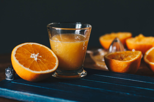 Oranges, juice and squeezer on wooden table - Fotó, kép