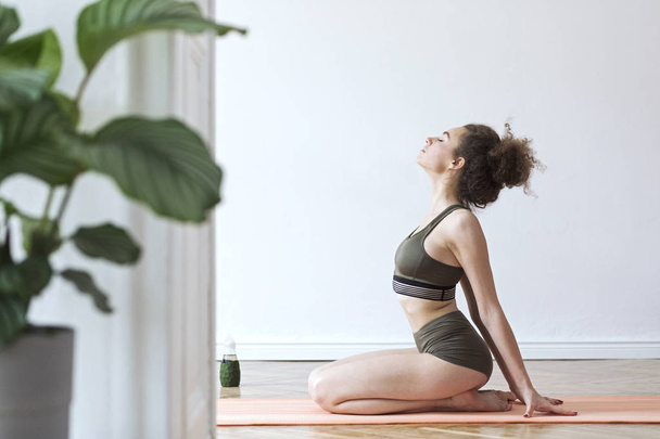 Young woman practicing yoga asana at home  - Foto, afbeelding