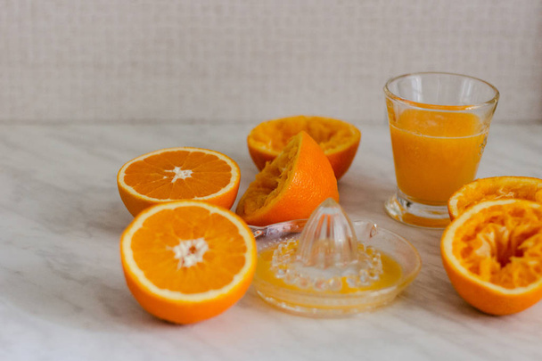 Oranges, juice and squeezer on marble table - Φωτογραφία, εικόνα