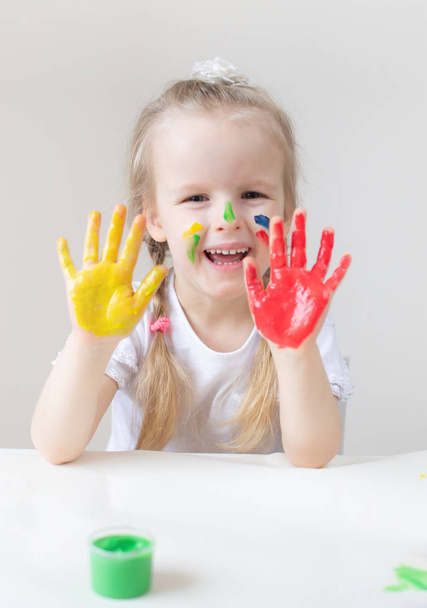 カラフルな手で白人の小さな女の子の絵がホームの早期教育学校幼児開発の子供のゲームのための準備で塗料します。 - 写真・画像