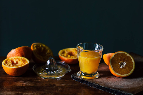 Oranges, juice and squeezer on wooden table - Fotó, kép