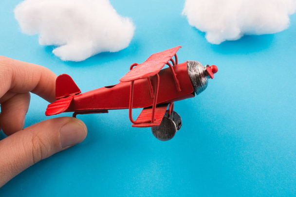 Avion modèle rouge de style rétro à la main, ciel bleu et nuages
 - Photo, image
