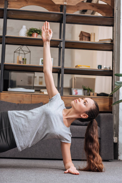 concentrated sportswoman doing side plank exercise at home  - Foto, Imagem