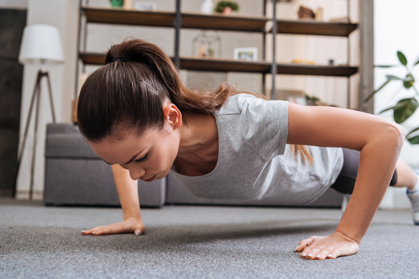 selective focus of concentrated sportswoman doing push ups at home - Foto, Imagem