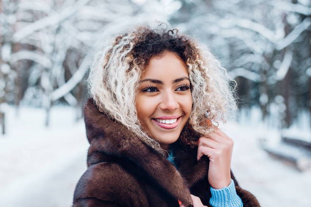 Close-up portrait of beautiful young afro american woman in winter forest - Фото, изображение