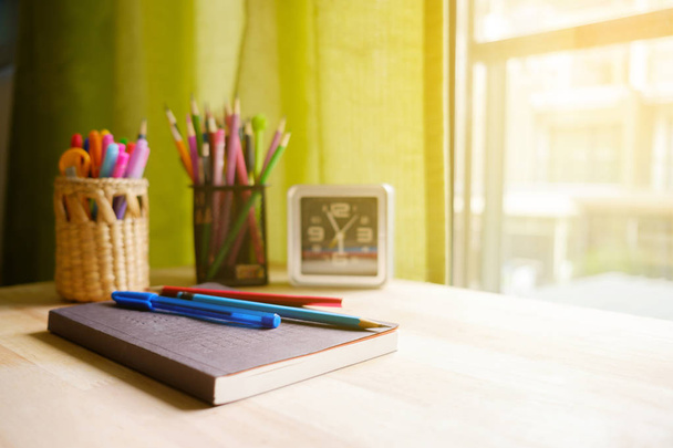 Livre stylo et crayon sur la table près de la fenêtre à la lumière chaude avec espace de copie
. - Photo, image