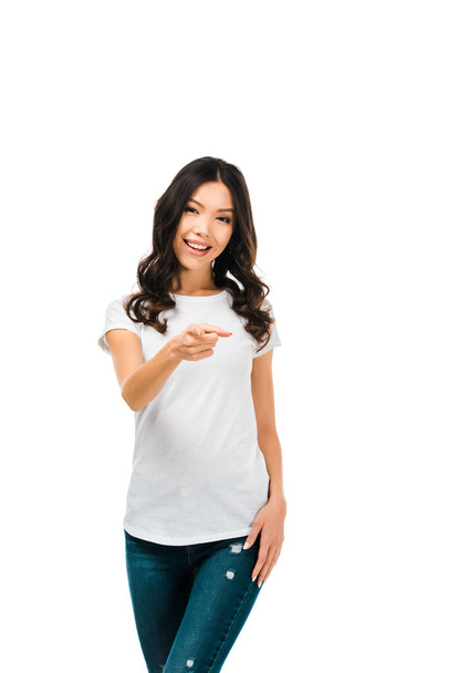 attractive brunette girl pointing with finger and smiling at camera isolated on white - Фото, зображення