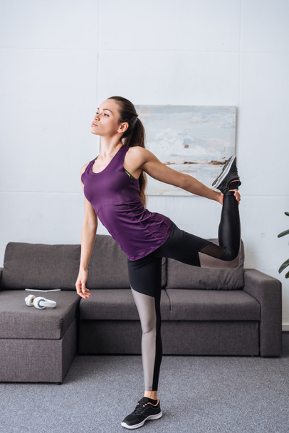 beautiful young sportswoman stretching before workout at home - Photo, Image