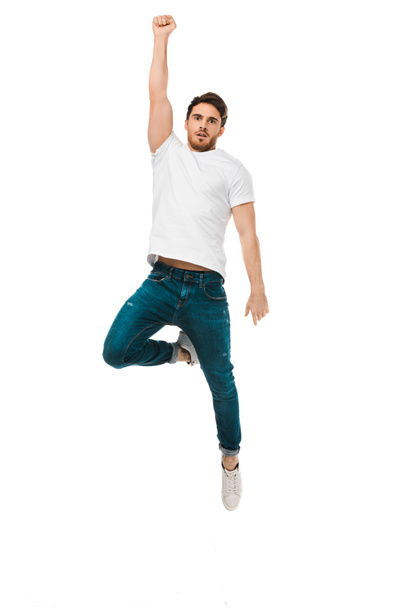 serious handsome man jumping with raised hand and looking at camera isolated on white - 写真・画像