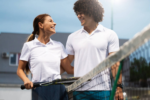 Couple of tennis players happy at the court after a match - Фото, изображение