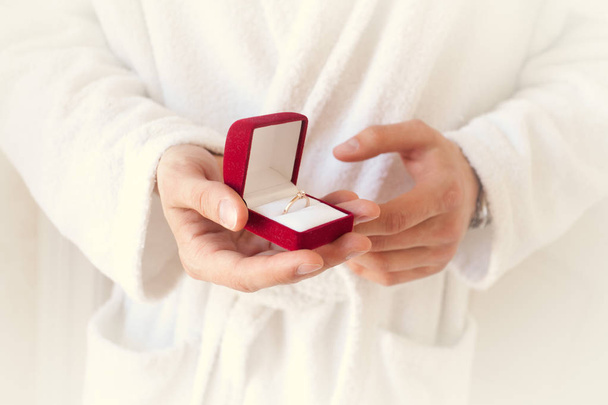 Pedido de casamento. A mão segura uma caixa de presente vermelha com um anel de ouro. Sentença. O melhor dia. Dá um anel. Fecha. Dia dos Namorados
 - Foto, Imagem