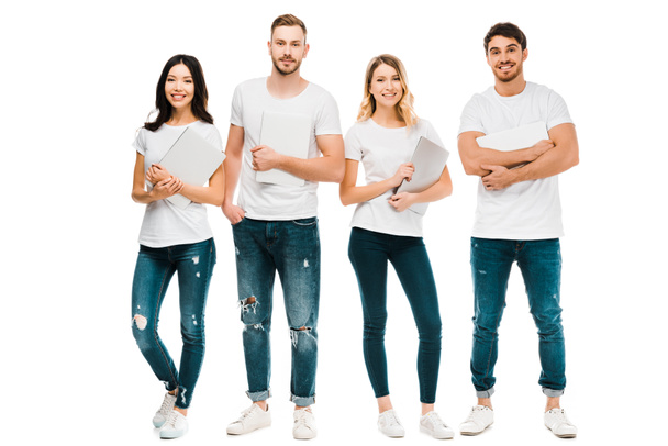 happy young people in white t-shirts and jeans holding laptops and smiling at camera isolated on white - Photo, Image