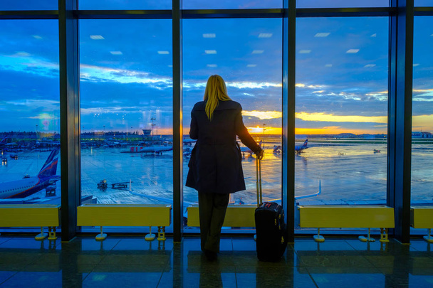 Une femme se tient près de la fenêtre de l'aéroport
 - Photo, image