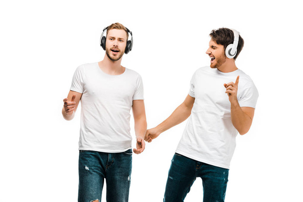 усміхнені молоді чоловіки слухають музику в навушниках і співають ізольовані на білому
  - Фото, зображення