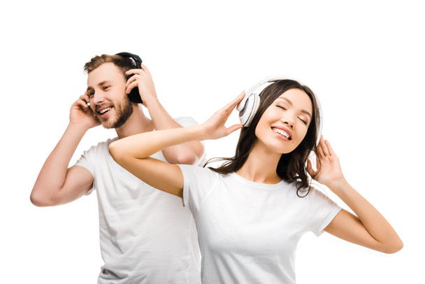 happy young couple in white t-shirts listening music in headphones isolated on white  - Fotografie, Obrázek