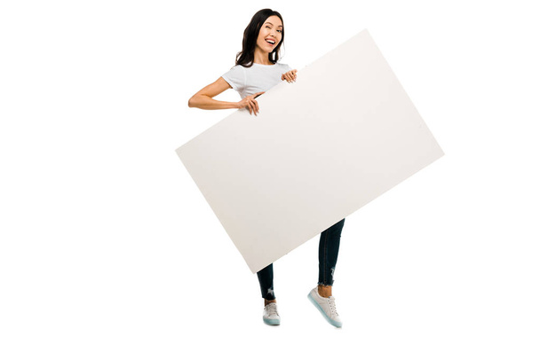 Szczęśliwa młoda kobieta przytrzymanie puste afisz i uśmiecha się do kamery na białym tle - Zdjęcie, obraz