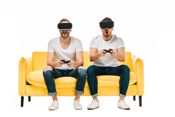 jóvenes emocionales en auriculares de realidad virtual jugando con joysticks aislados en blanco
  - Foto, Imagen