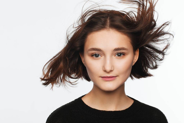 Portrait of a beautiful teen girl in a black sweater on a white background. Fan-blown hair - Fotografie, Obrázek