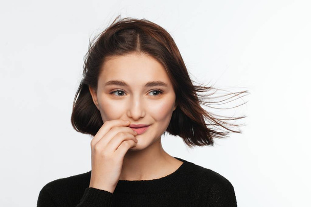 Portrait of a beautiful teen girl in a black sweater on a white background. Fan-blown hair - Фото, изображение