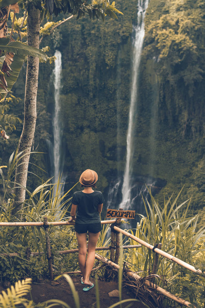 Young woman posing on a great Sekumpul waterfall in the deep rainforest of Bali island, Indonesia. - Zdjęcie, obraz