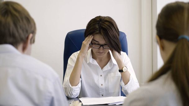 Women boss in stress of job employees. Businesswoman tired of mistakes in work of employees. Attractive boss suffers from headache and fatigue, removes glasses in office - Fotó, kép