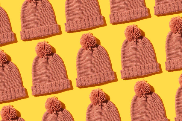 Tejer sombreros de invierno organizados en fila sobre fondo amarillo
 - Foto, imagen