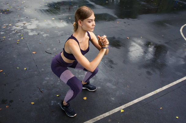 Modèle de remise en forme dans un haut de sport et leggings faire des exercices sportifs sur les terrains de sport dans le parc. Forme féminine parfaite. Entraînement sous la pluie
 - Photo, image